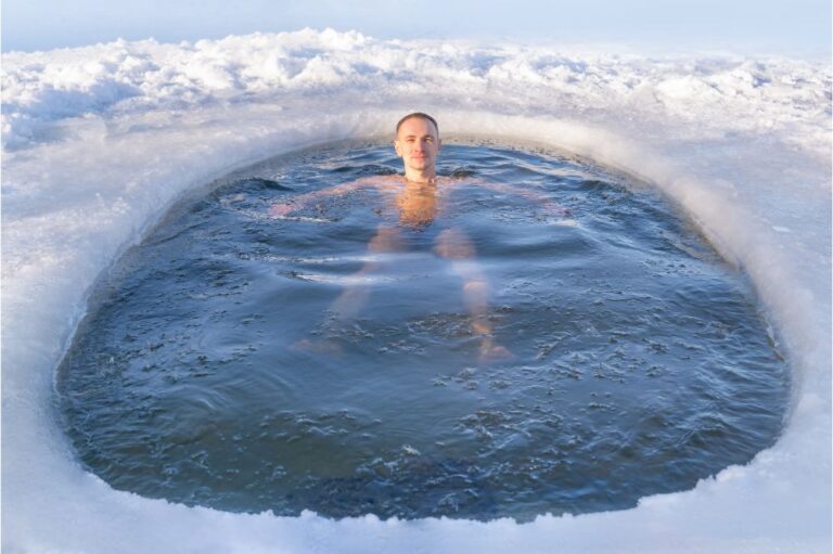 man swims in cold water in an ice hole in a winter forest